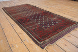 Antique Belouch runner detail: repeating pomegranate starburst field and meandering vine border.