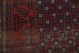 Antique Belouch rug: madder red, navy, dark brown starbursts, vine border, visible foundation wear.