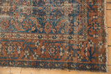 Detail of antique Malayer rug showing worn Herati motif, madder root border, and tattered side.