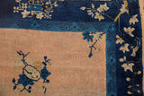 Abrashed peach field, indigo blue border with ivory floral motifs on antique Peking rug.