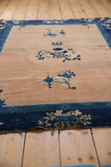 Abrashed peach field and indigo border with floral motifs on an antique Peking rug.