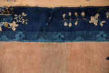 Antique Peking rug border showing indigo blue floral motifs, abrashed coffee brown field, and wear.