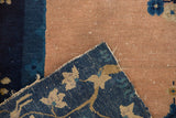 Knot heads visible on pale peach foundation and indigo blue floral pile of antique Peking rug.