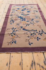 Fringed end of vintage Chinese Art Deco runner, showing mauve border and beige field vinery.