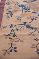 Beige Nichols Art Deco rug detail: cobalt blue bird, vinery, saffron flower, mauve border, pile wear.