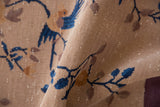 Beige Art Deco rug's folded edge, revealing cobalt blue vinery, bird, and soft pile texture.