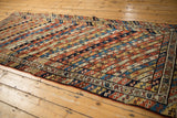 Full length view of an antique Kurdish runner showing its vibrant, diagonally striped ribbon pattern.