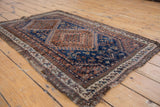 Tattered edge detail of the antique Afshar rug with indigo and chestnut geometric border.