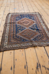 Frayed fringework and geometric borders of the antique Afshar rug in indigo and chestnut.