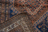 Antique Afshar rug edge showing tattered pile, geometric indigo and chestnut brown patterns.