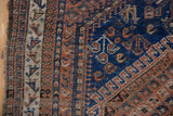 Antique Afshar rug with visible tattered edge, intricate indigo, chestnut, and ivory geometric border.