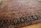 Vintage Lilihan carpet's aged edge, with navy blue floral border and raspberry field.