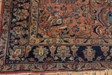 Vintage Lilihan carpet with navy blue floral border, dusty raspberry field, and worn fringe.