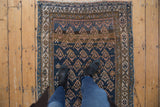 Antique Kurdish rug's geometric boteh pattern in navy, bronze, and ivory with abrashed ground.