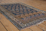 Geometric boteh pattern in navy, bronze, ivory with visible pile wear and faint foundation.