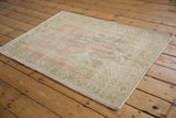 Vintage Distressed Oushak rug corner showing pale blush, mint border, and intact side selvage.