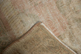 Folded corner of a vintage Oushak rug, showing distressed pile, hand-knotted foundation, and selvage.