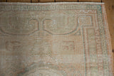 Close-up of distressed Oushak rug corner, showing worn pile, geometric blush and green border.