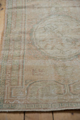 Distressed Oushak rug texture showing even wear, faint foundation, and soft ivory, blush, seafoam tones.