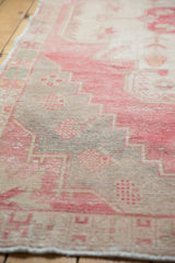 Distressed vintage Oushak rug showing muted cherry red, sand, and mint geometric motifs.