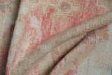 Vintage distressed Oushak rug texture showing mostly even wear with faded blush and beige tones.