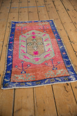 Distressed vintage Oushak rug with pink abrashed field, lozenge medallion, and royal blue border.