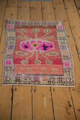 Distressed Oushak rug corner showing textured pile, blush pink field, and geometric border.