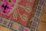 Distressed Oushak rug mat corner, worn pile showing geometric border and color pops.