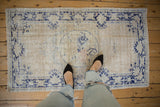 Distressed Oushak rug's center medallion with faded ivory, blue, and blush tones.