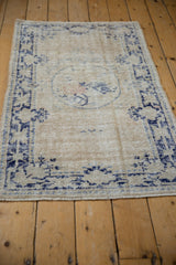 Distressed vintage Oushak rug corner with faded navy blue border and worn ivory pile.