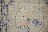 Distressed Oushak rug texture with mostly even wear, faded navy, and blush floral motifs.