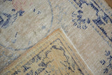 Distressed Oushak rug pile texture showing faded blue designs and intact selvage.