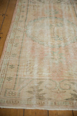 Distressed Oushak runner showing low pile and soft blush, beige, mint blue pattern.