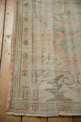 Worn side selvage and blush geometric running T border on distressed Oushak rug.