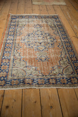 Distressed Oushak rug with worn apricot, ivory, and faded blue grid panel and star border.