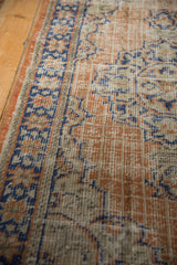 Distressed vintage Oushak rug section with apricot and faded blue geometric patterns, revealing worn knot heads.