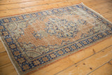 Distressed Oushak rug's star border and grid pattern in apricot, ivory, faded blue.