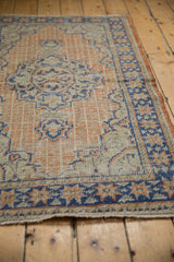 Close-up of distressed vintage Oushak rug with apricot and blue geometric grid.