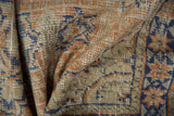 Distressed vintage Oushak rug pile with apricot, ivory, and faded midnight blue pattern.