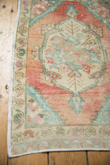 Vintage distressed Oushak rug's side selvage, revealing mostly even wear, blush, and faded teal floral details.