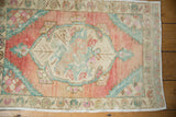 Distressed vintage Oushak rug corner, showing faded blush field and floral border.