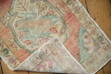 Distressed vintage Oushak rug's hand-knotted back, side cord, and blush seafoam pile.