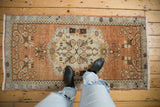 Distressed vintage Oushak runner with floral medallion and copper, charcoal, ivory tones.