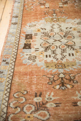 Vintage Oushak runner's soft copper field, distressed texture, and slate blue border with selvage.