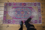 Distressed vintage Oushak rug, showing its plum and blue colors and soft texture underfoot.