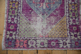 Distressed Oushak rug corner with plum, green, saffron seed motifs, worn foundation.