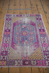 Distressed Oushak rug with plum, violet, saffron yellow diamond medallion, showing worn texture.