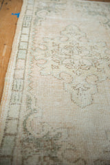Distressed Oushak runner showing muted seafoam green patterns on worn, antique ivory pile.