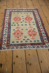 Distressed Oushak rug's brick red geometric starbursts, navy motifs, and visible worn pile.