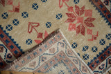 Distressed caramel Oushak pile with red, navy motifs, revealing hand knotted backing weave.